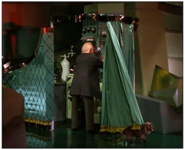 A Person in a Suit Operating a Machine Behind a Curtain