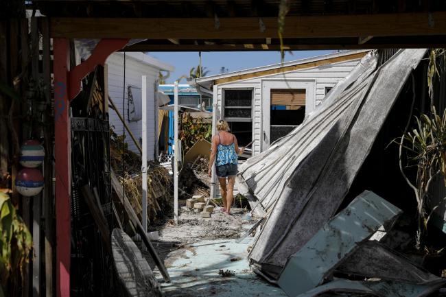 &copy Bloomberg. A resident walks inside her damaged house following Hurricane Ian in Matlacha, Florida, US, on Wednesday, Oct. 5, 2022. President Biden and Governor DeSantis have feuded over political issues, including migrants, but are coordinating on assistance for Floridians hit by a hurricane Biden's called 