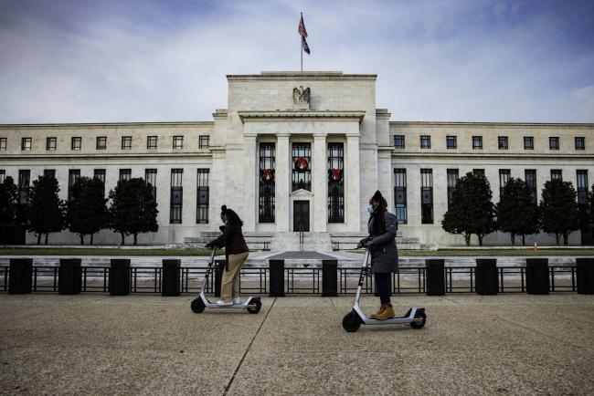 © Bloomberg. Visitors ride electric scooters near the Marriner S. Eccles Federal Reserve building in Washington, D.C., U.S., on Saturday, Nov. 20, 2021. The Federal Reserve looks on course to consider a more rapid drawdown of its mammoth bond-buying program just weeks after it instituted a plan to scale the purchases back in a methodical manner.