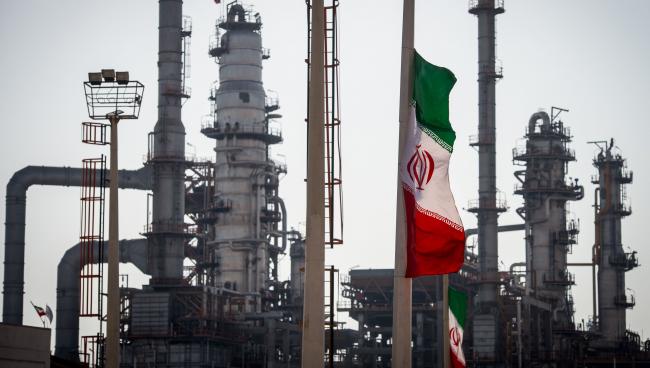 © Bloomberg. An Iranian national flag flies near gas condensate processing facilities in the new Phase 3 facility at the Persian Gulf Star Co. (PGSPC) refinery in Bandar Abbas, Iran.