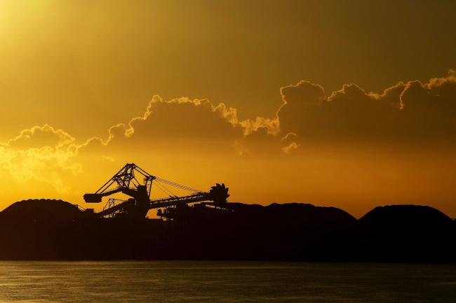 © Bloomberg. A stacker-reclaimer operates next to stockpiles of coal at the Newcastle Coal Terminal in Newcastle, New South Wales, Australia, on Friday, March 26, 2021. The one-in-100 year flooding event in Australia in recent days forced coal producers from Glencore Plc to Yancoal Australia Ltd. to cut output, while Whitehaven Coal Ltd. said there is a backlog of ships at the key Port of Newcastle export terminal.