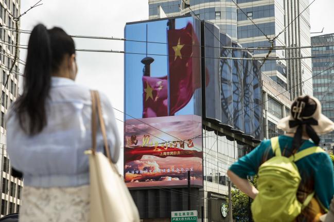 © Bloomberg. A public screen displays an image of Chinese flags in Shanghai, China, on Wednesday, Aug. 18, 2021. President Xi Jinping said China must pursue 