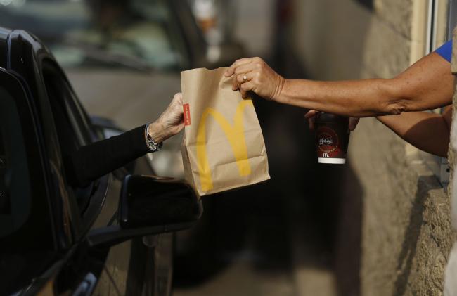 © Bloomberg. A worker passes a bag of food to a customer at the drive-thru window at a McDonald's fast food restaurant in White House, Tennessee. Photographer: Luke Sharrett/Bloomberg