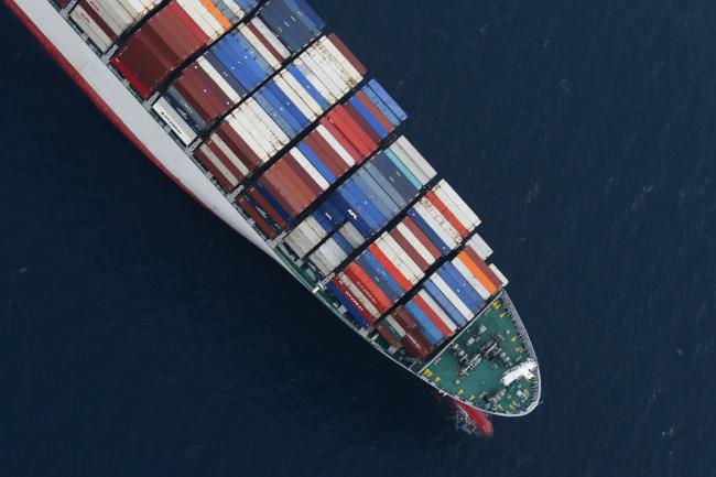 © Bloomberg. An Orient Overseas Container Line (OOCL) container ship waits to unload cargo in this aerial photograph taken above the Port of Los Angeles in Los Angeles, California, U.S., on Wednesday, Feb. 18, 2015. United Steelworkers members who help run crude terminals at a California port are threatening to join a national oil workers' strike at U.S. refineries.