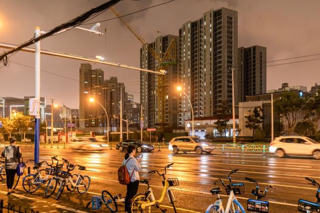 © Bloomberg. Traffic moves along a street near an residential area in Shanghai, China, on Wednesday, Sept. 29, 2021. The National Development and Reform Commission will let power prices reasonably reflect changes in demand, supply and costs, it said in a statement on measures to ensure power supply through winter and spring seasons. Photographer: Qilai Shen/Bloomberg