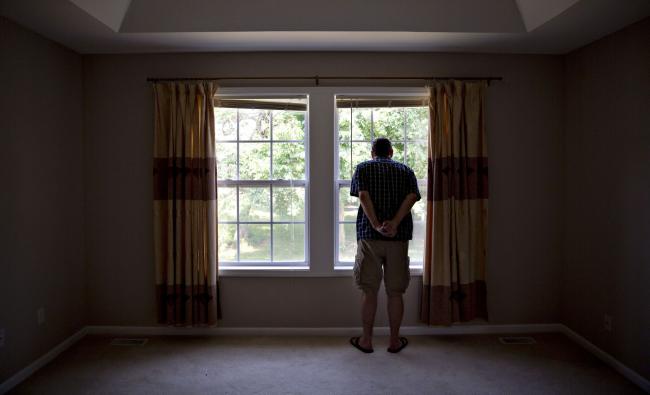 © Bloomberg. A prospective home buyer looks out the master bedroom window at a house for sale in Dunlap, Illinois.