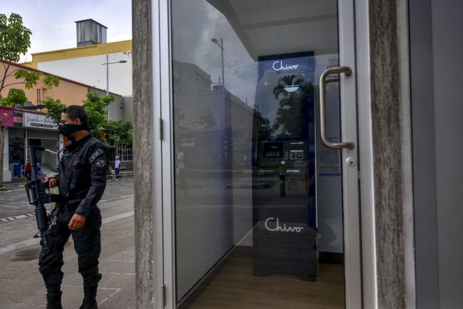 © Bloomberg. A police officer stands guard outside a Chivo Bitcoin automated teller machine (ATM) at Gerardo Barrios plaza in San Salvador, El Salvador, on Saturday, Aug. 28, 2021. El Salvador began installing Bitcoin ATMs, allowing its citizens to convert the cryptocurrency into U.S. dollars and withdraw it in cash, as part of the government’s plan to make the token legal tender.