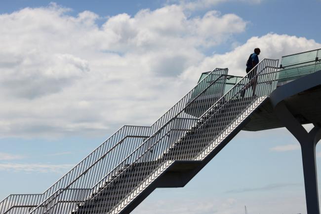 © Bloomberg. A pedestrian walks up stairs to a footbridge in Auckland, New Zealand, on Tuesday, Nov. 23, 2021. New Zealand's central bank is expected to raise interest rates for a second straight month and signal a more aggressive tightening cycle to contain inflation amid a labor shortage. Photographer: Brendon O'Hagan/Bloomberg