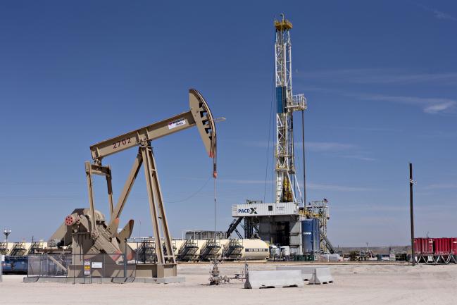 © Bloomberg. A pumpjack operates near a Nabors Industries Ltd. drill rig standing over an oil well for Chevron Corp. in the Permian Basin near Midland, Texas, U.S., on Thursday, March 1, 2018. Chevron, the world's third-largest publicly traded oil producer, is spending $3.3 billion this year in the Permian and an additional $1 billion in other shale basins. Its expansion will further bolster U.S. oil output, which already exceeds 10 million barrels a day, surpassing the record set in 1970.