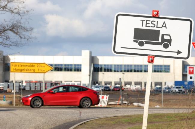 © Bloomberg. A road sign for the Tesla Inc. Gigafactory construction site in Gruenheide, Germany, on Friday, Feb. 11, 2022. Progress at the site has been slower than hoped, with backlash from environmental groups concerned about water use and wildlife postponing the start of production by several months. Photographer: Liesa Johannssen-Koppitz/Bloomberg