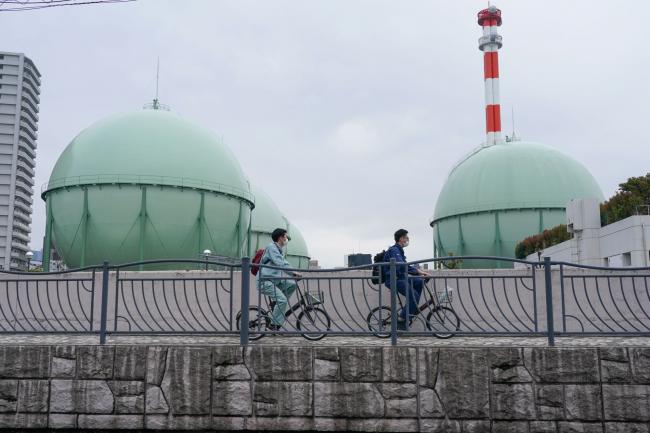 © Bloomberg. Cyclists travel past Tokyo Gas Co. storage tanks at the company's Hiranuma facility in Yokohama, Japan, on Wednesday, April 20, 2022. Japan’s imports jumped 31% in March from a year ago to a record value, led by crude oil, coal and natural gas, and that will translate into higher power bills in the nation that relies heavily on others for its energy resources. Photographer: Toru Hanai/Bloomberg