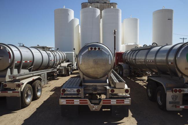 © Bloomberg. Tanker trucks sit in front of storage silos in Sunray, Texas, U.S., on Saturday, Sept. 26, 2020. After all the trauma the U.S. oil industry has been through this year -- from production cuts to mass layoffs and a string of bankruptcies -- many producers say they’re still prioritizing output over reducing debt. Photographer: Angus Mordant/Bloomberg