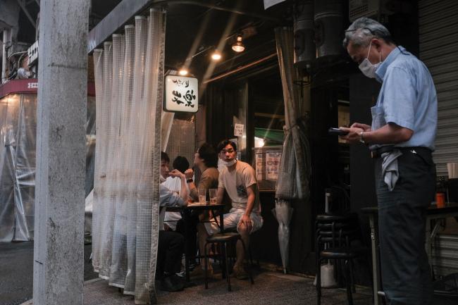 © Bloomberg. Customers dine at an Izakaya bar at the Ameya Yokocho market in the Ueno District of Tokyo, Japan, on Friday, July 2, 2021. Confidence among Japan’s large manufacturers rebounded to the highest since 2018 and big businesses of all stripes ramped up investment plans in a sign that companies see an end to the pandemic even as virus restrictions grind on at home.