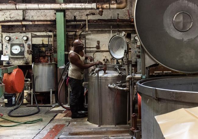 © Bloomberg. A worker checks on a dyeing machine at a raw stock dye house in Philadelphia, Pennsylvania.