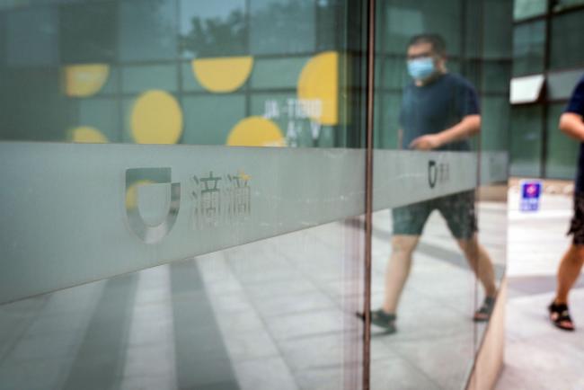 © Bloomberg. A pedestrian pass a logo at the Didi Global Inc. headquarters in Beijing, China, on Monday, July 5, 2021. China expanded its latest crackdown on the technology industry beyond Didi to include two other companies that recently listed in New York, dealing a blow to global investors while tightening the government’s grip on sensitive online data. Photographer: Yan Cong/Bloomberg