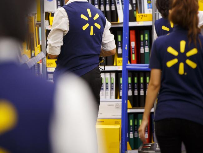 © Bloomberg. Employees restock shelves at Wal-Mart