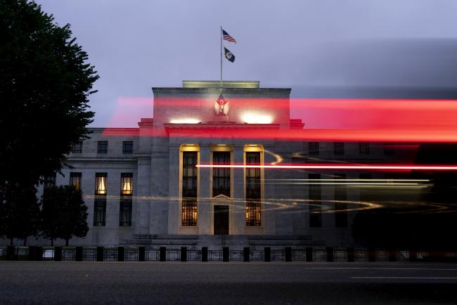 © Bloomberg. Light trails from a vehicle in front of the Marriner S. Eccles Federal Reserve building in Washington, D.C., U.S., on Saturday, June 26, 2021. The Federal Reserve might consider an interest-rate hike from near zero as soon as late 2022 as the labor market reaches full employment and inflation is at the central bank's goal.