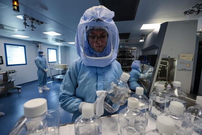 © Bloomberg. Employees in biohazard suits prepare raw materials for messenger RNA (mRNA), the first step of Covid-19 vaccine production, at the BioNTech SE laboratory in Marburg, Germany, on Saturday, March 27, 2021. BioNTech and Pfizer Inc. raised this year’s production target for their Covid-19 vaccine to as many as 2.5 billion doses, with the German biotech’s chief executive predicting a version of the shot that can be stored in refrigerators will be ready within months.
