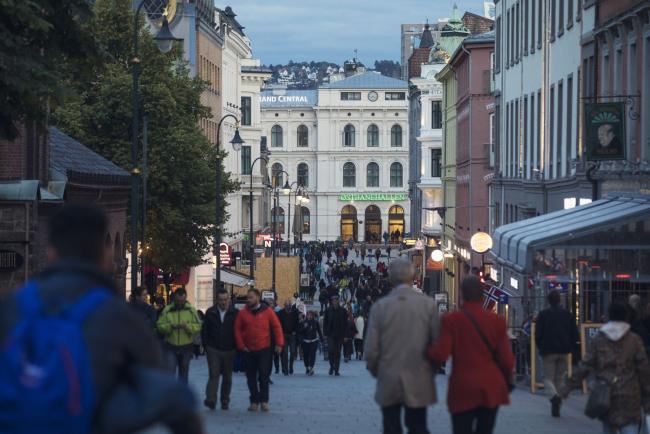 © Bloomberg. Pedestrians walk past restaurants and retail stores near Karl Johan's gate in Oslo, Norway, on Thursday, Sept. 21, 2017. Norway’s sovereign wealth fund hit $1 trillion for the first time on Tuesday, driven higher by climbing stock markets and a weaker U.S. dollar.