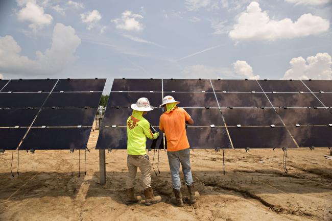 © Bloomberg. Workers install solar panels at a solar generating facility in Milligan, Tennessee.