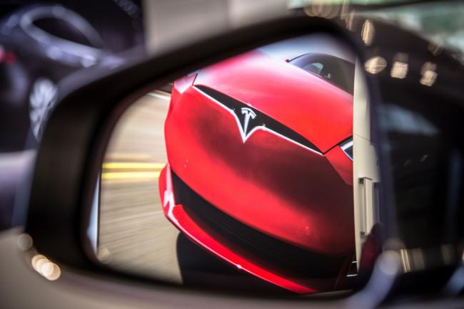 © Bloomberg. A badge sits on the hood of a Model S electric vehicle displayed inside a Tesla Inc. store in Barcelona, Spain, on Thursday, July 11, 2019. Tesla is poised to increase production at its California car plant and is back in hiring mode, according to an internal email sent days after the company wrapped up a record quarter of deliveries.