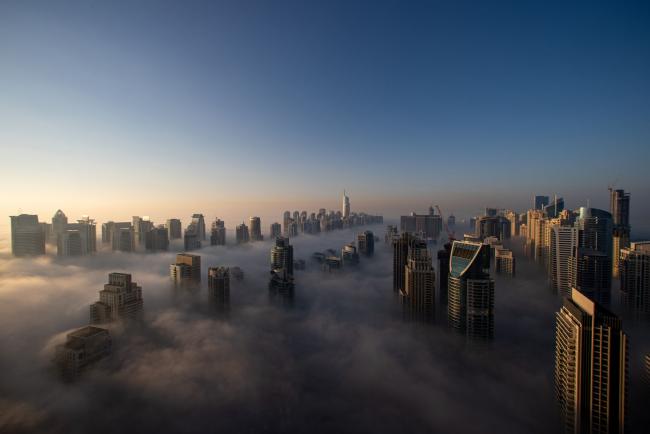 © Bloomberg. Morning fog shrouds residential and commercial skyscrapers in the Jumeirah Lakes Towers district of Dubai, United Arab Emirates, on Sunday, Jan. 17, 2021. Dubai is hoping one of the world’s fastest vaccination programs and rapid testing technology will help achieve its goal of holding the Expo 2020 event this year, after the coronavirus pandemic forced a delay. Photographer: Christopher Pike/Bloomberg