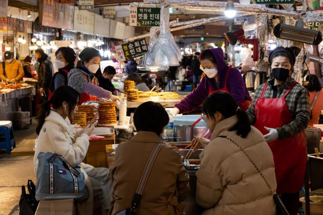 © Bloomberg. People dine at a food stall in Gwangjang Market in Seoul, South Korea, on Thursday, March 3, 2022. South Korea kicked off two days of early voting on March 4 as the country battles a record wave of coronavirus infections, while data showed inflation unexpectedly accelerated in February as rising costs weighed on voters.