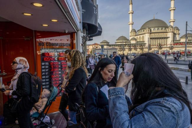 © Bloomberg. Customers at a currency exchange bureau on Taksim square in Istanbul, Turkey, on Friday, Oct. 15, 2021. Turkish President Recep Tayyip Erdogan fired monetary policy makers wary of cutting interest rates further, driving the lira to record lows against the dollar with his midnight decree.
