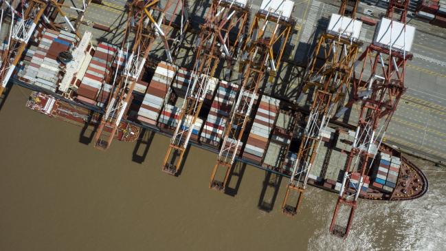 © Bloomberg. Gantry cranes next to a container ship at the Yangshan Deepwater Port in Shanghai, China, on Friday, April 9, 2021. China is scheduled to release trade figures on April 13. Photographer: Qilai Shen/Bloomberg