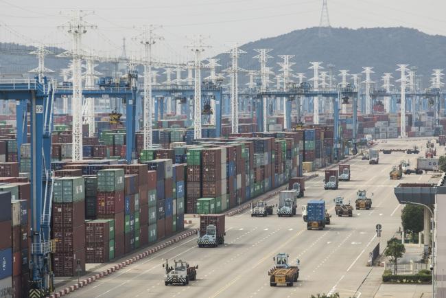 © Bloomberg. Containers sit stacked next to gantry cranes as trucks operate at the Port of Ningbo-Zhoushan in Ningbo, China, on Wednesday, Oct. 31, 2018. President Donald Trump wants to reach an agreement on trade with Chinese President Xi Jinping at the Group of 20 nations summit in Argentina later this month and has asked key U.S. officials to begin drafting potential terms, according to four people familiar with the matter.
