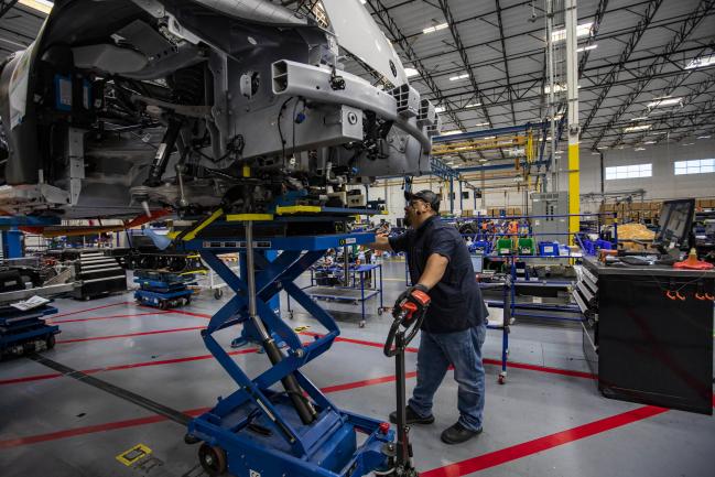 © Bloomberg. A worker joins the engine and chassis to the body of a Karma GS-6 electric vehicle on the production line inside the Karma Automotive LLC plant in Moreno Valley, California, U.S., on Friday, Aug. 13, 2021. Growth in U.S. manufacturing slowed for a second straight month in July amid ongoing supply-chain problems, reported the Associated Press. Photographer: Jill Connelly/Bloomberg