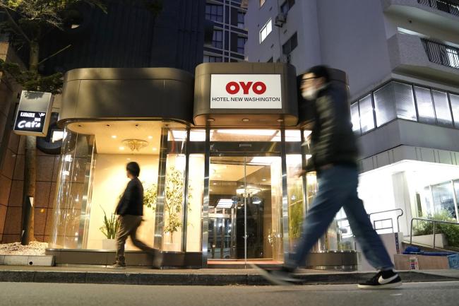 © Bloomberg. Pedestrians walk past an Oyo hotel, operated by Oyo Hotels Japan G.K., in Tokyo, Japan, on Monday, Jan. 27, 2020. Oyo has drawn particular attention in SoftBank Group Corp.’s portfolio of startups because of its similarities to WeWork. Both are trying to change traditional real estate businesses with technology. Both have charismatic young founders. Now, skeptics say Oyo could also fall short, further undermining Son’s grand ideas about technology investing.